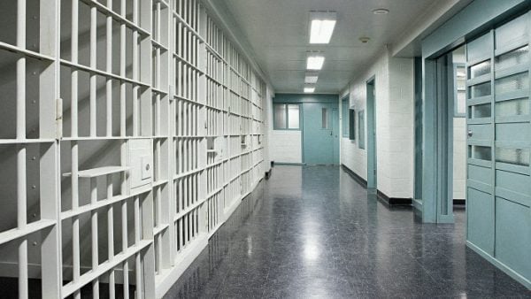 A bright and empty corridor in a prison facility.