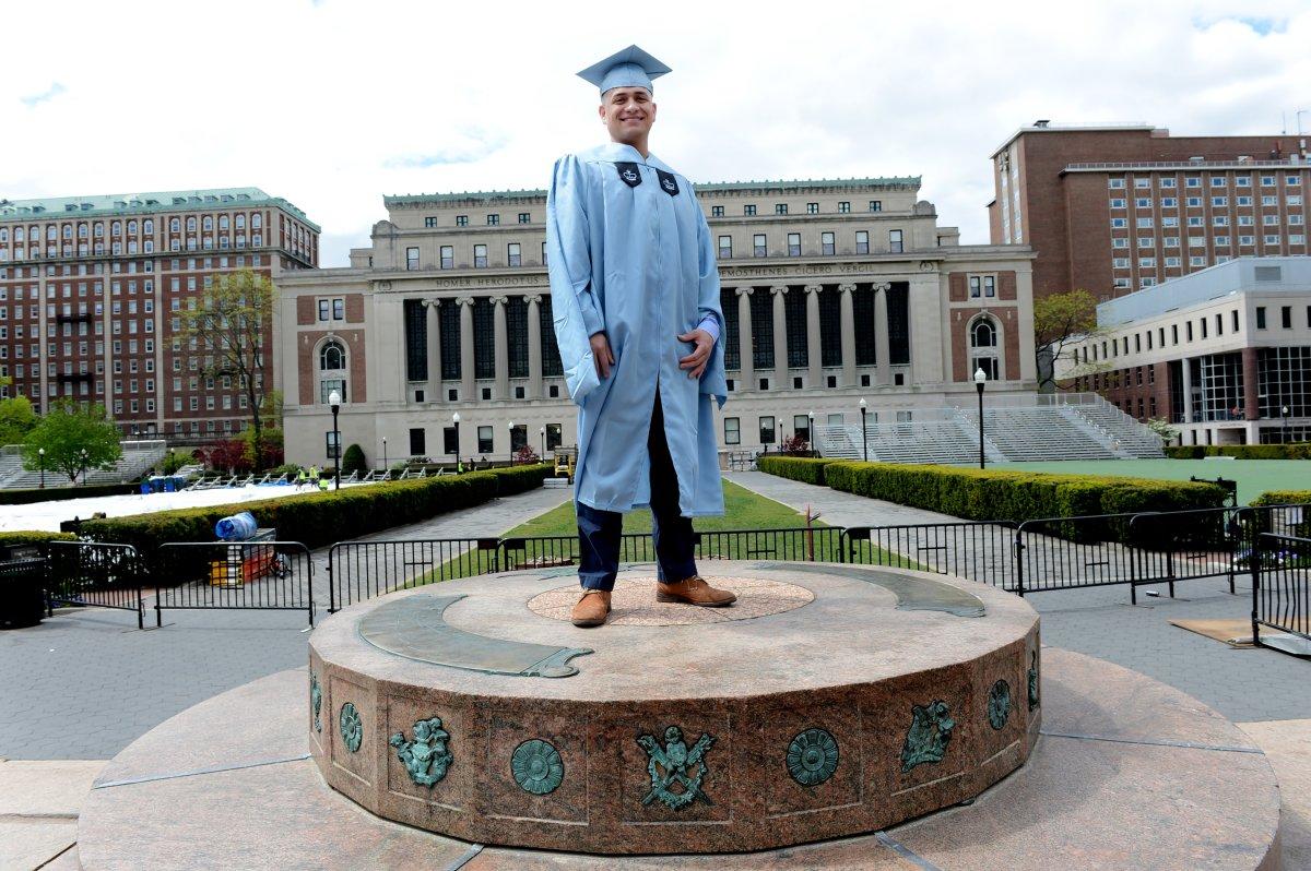 BPI alumnus standing in cap and gown in front of the Butler Library at Columbia University.