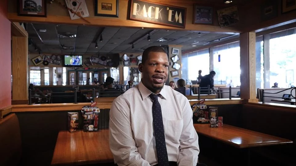 Marcellus Benbow sitting in an Applebee's restaurant and speaking.