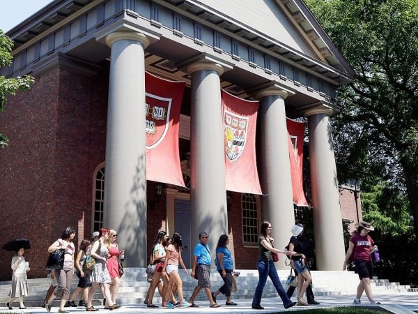 A group of people walking past a building on the Harvard University campus.