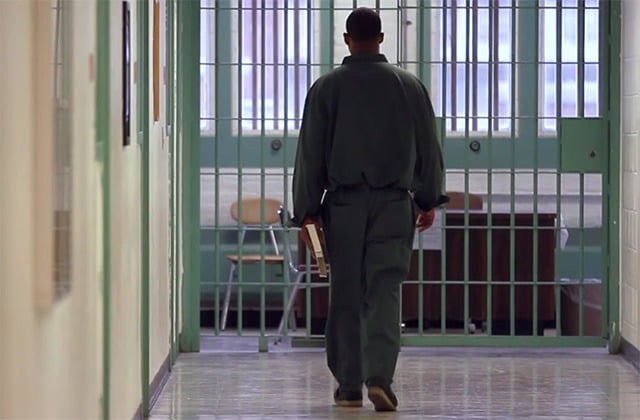 BPI student carries a book through a prison corridor.