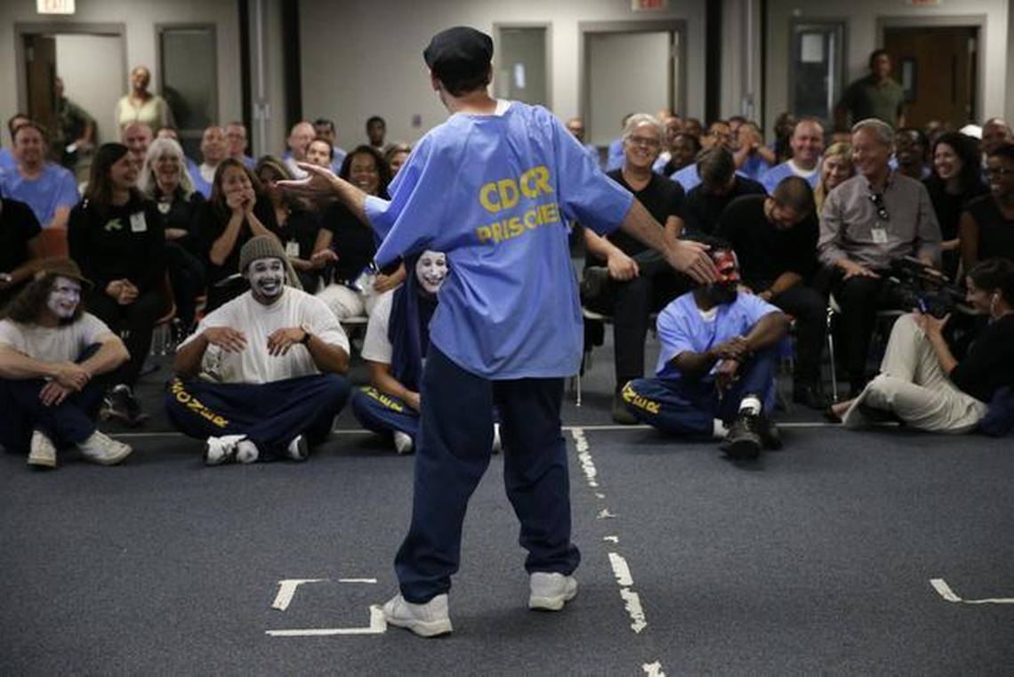 A man stands in front of a crowd and performs during an Actors' Gang Prison Project workshop.