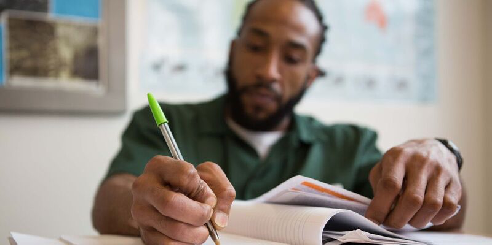 Close up of BPI Student writing in notebook with camera focus on his pen.