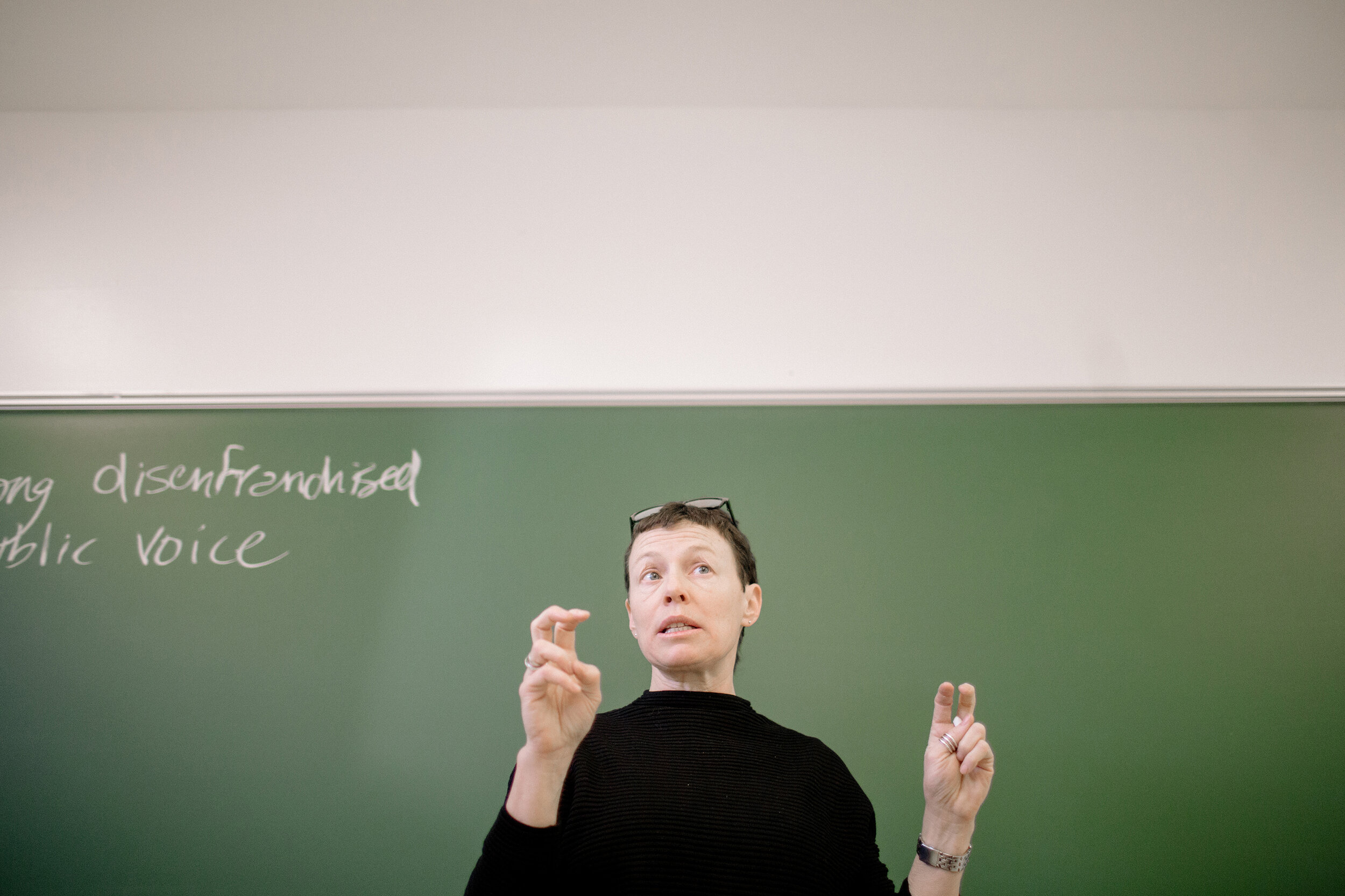 Professor Delia Mellis speaking in front of a chalkboard.