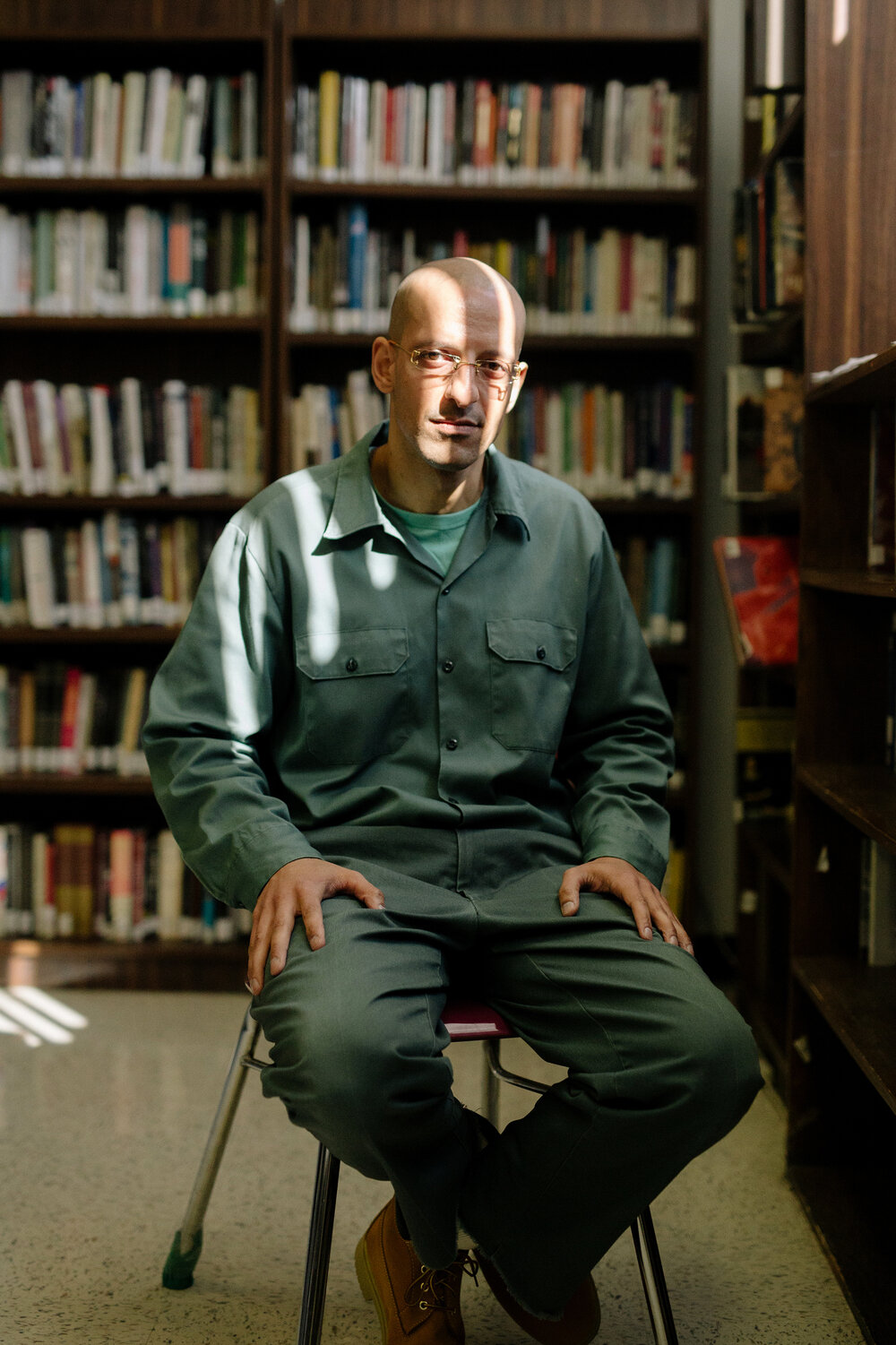 BPI student, Glenn Rodriguez, sitting in a chair in the library.