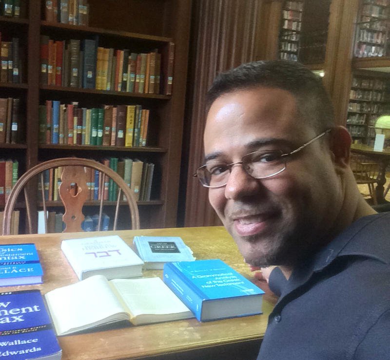 BPI alumnus smiling at a table in the library.