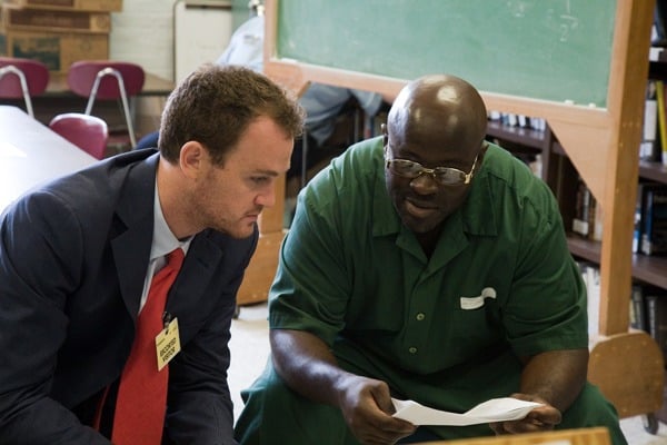 Max Kenner sits beside a BPI student as they read a document the student is holding.