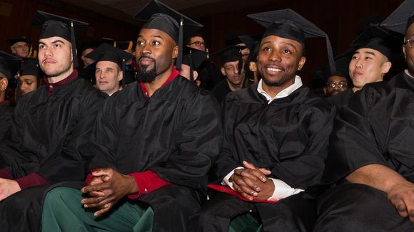 BPI students in caps and gowns seated and smiling while listening to the commencement speakers.