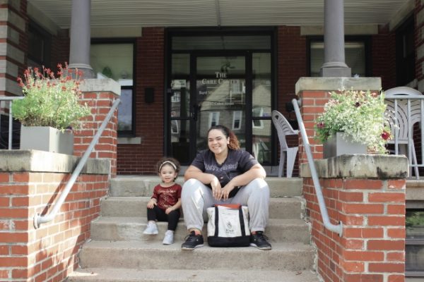 Bard Microcollege student sitting with a young girl on the steps of the Care Center.