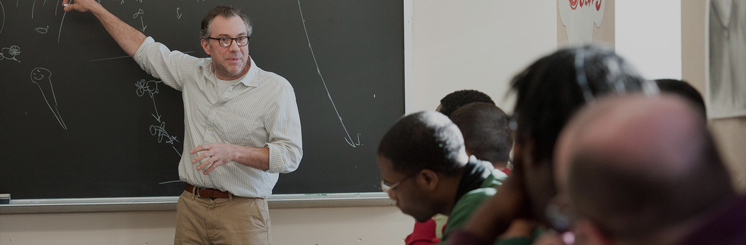 Professor gesturing at chalkboard. Copyright China Jorrin.