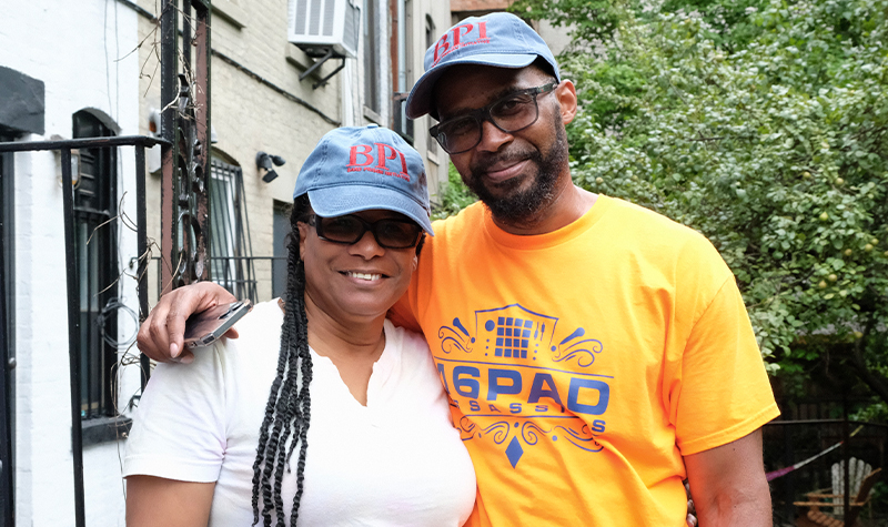 Two alumni smiling with BPI baseball hats.