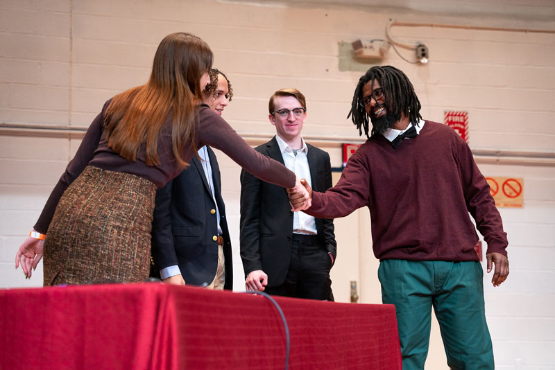 BPI student shaking hands with debate competitors from Brown.