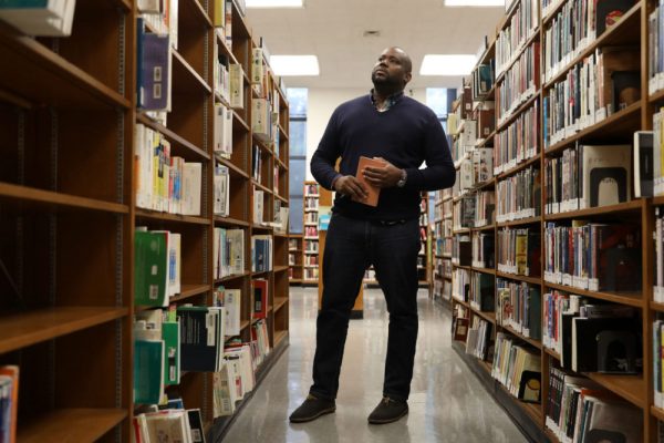 Microcollege student posing for a portrait in the stacks at the Brooklyn Public Library.