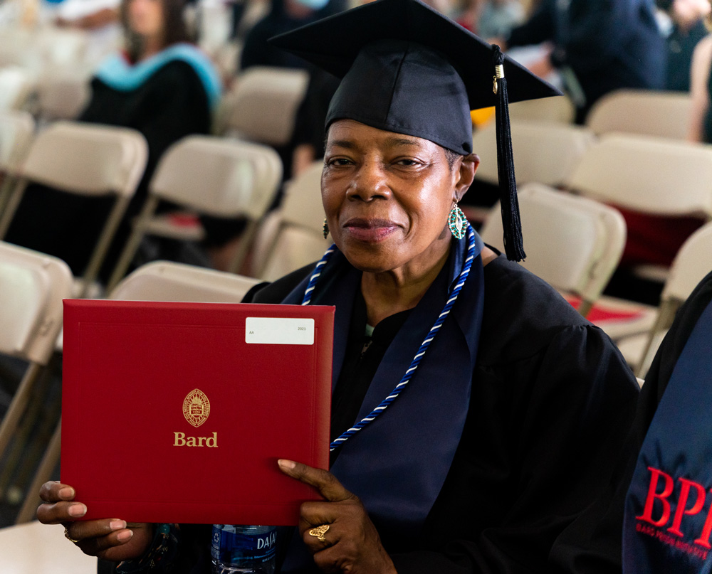 A graduate at commencement holds up her diploma folder.