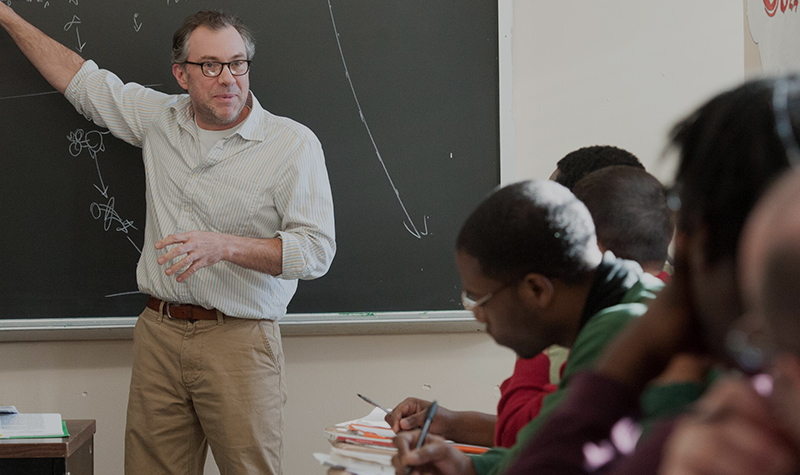 Professor gesturing at chalkboard. Copyright China Jorrin.