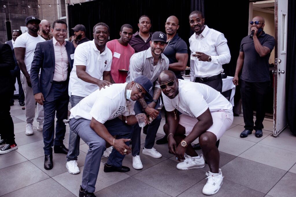 A large group of alumni pose at a rooftop summer event.