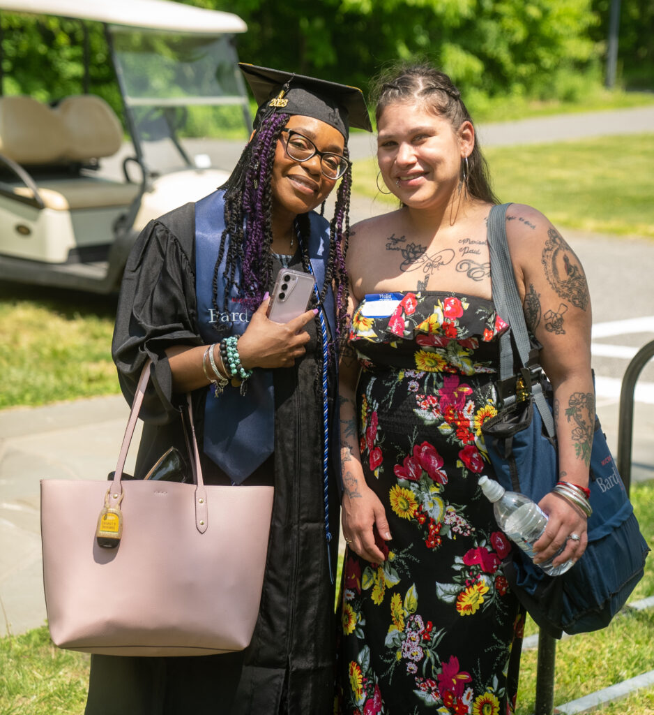 A microcollege graduate poses with her friend at commencement.