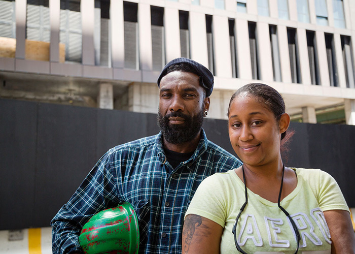 Two alumni posing with construction helmet.