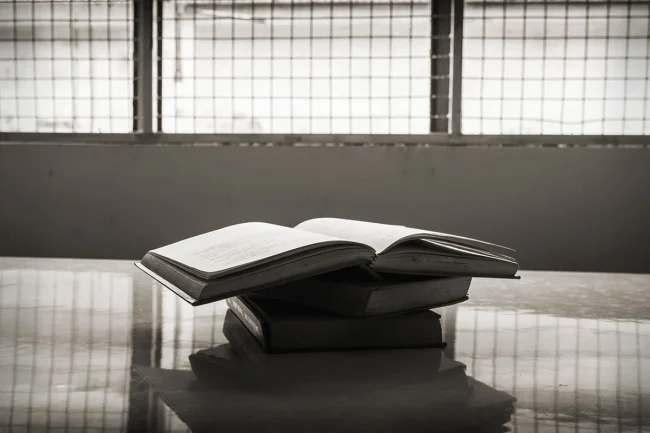 A stack of books on a table in front of a window