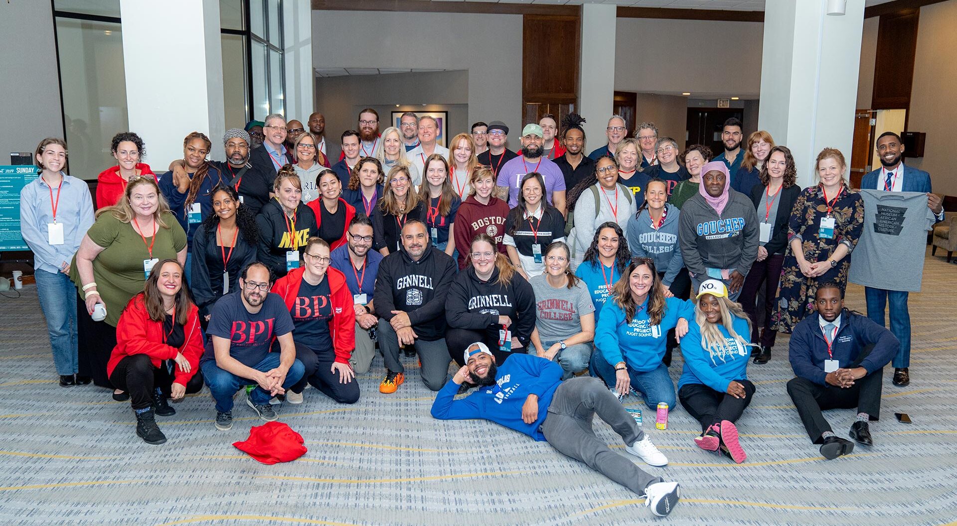 Large group of BPI Consortium partners wearing shirts with college and university logos.