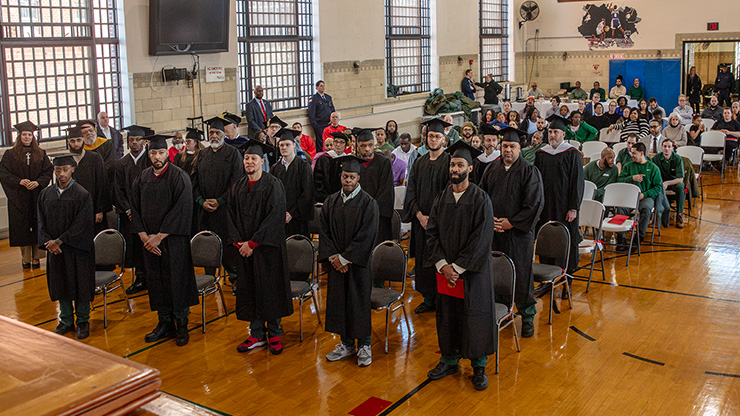 Graduates in cap and gown standing at ceremony.